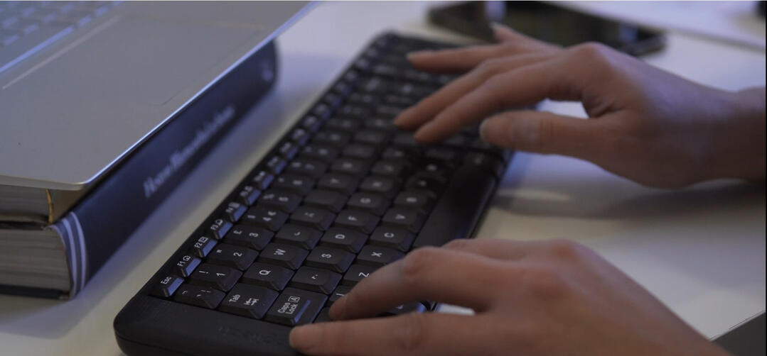 Amelia Epton – Expert Grant Writer Helping Charities Secure Funding. Amelia Epton focused on grant writing, typing on her keyboard to secure funding for charities.